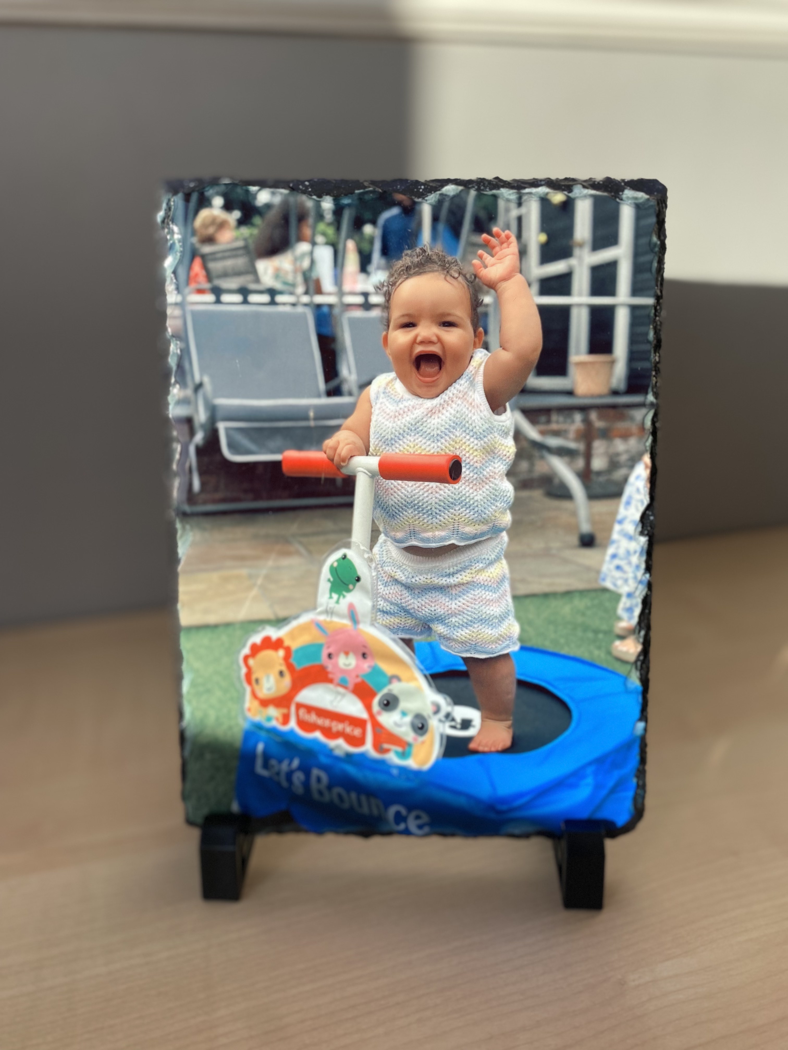 Slate photo of a happy baby on a small trampoline